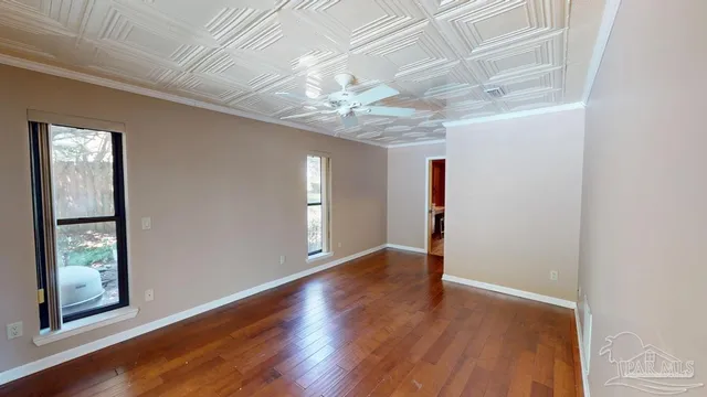 an empty room with wooden floor chandelier and windows