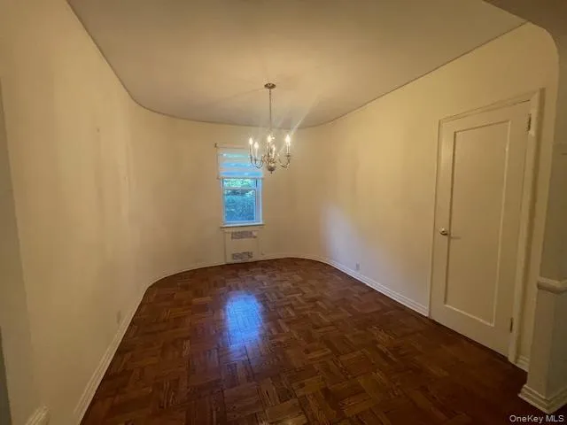 a view of an empty room and chandelier fan