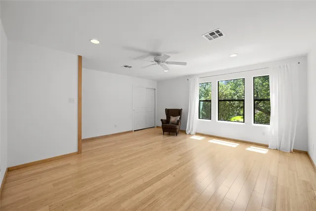 a view of an empty room with a window and wooden floor