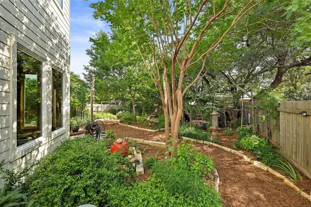 a backyard of a house with table and chairs plants and large tree