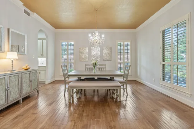 a view of a kitchen with kitchen island granite countertop a stove a sink and a dining table with wooden floor