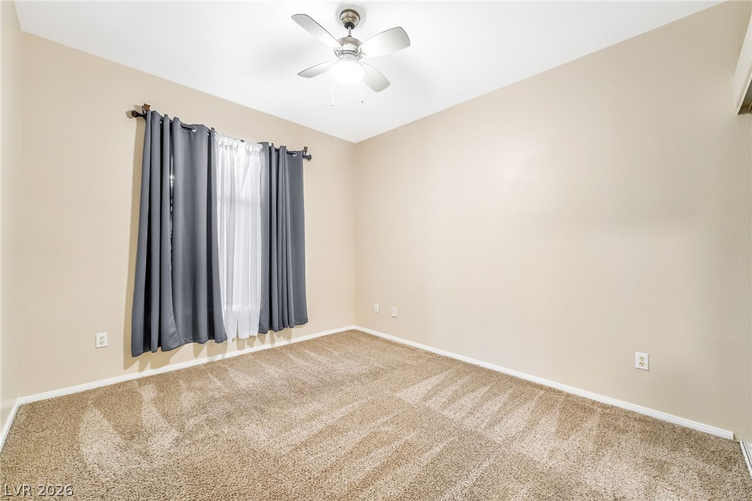 2050 West Warm Springs Road, Unit 2411 Henderson, NV 89014 - Photo 27 of 37 A well-lit bedroom features plush carpeting and a ceiling fan, offering a comfortable retreat.