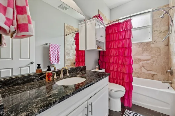 a bathroom with a granite countertop sink vanity mirror bathtub shower and a toilet