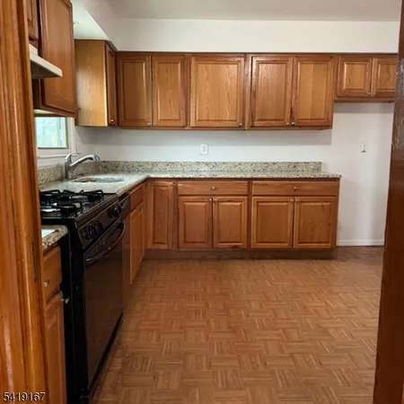 a kitchen with granite countertop a stove top oven sink and cabinets