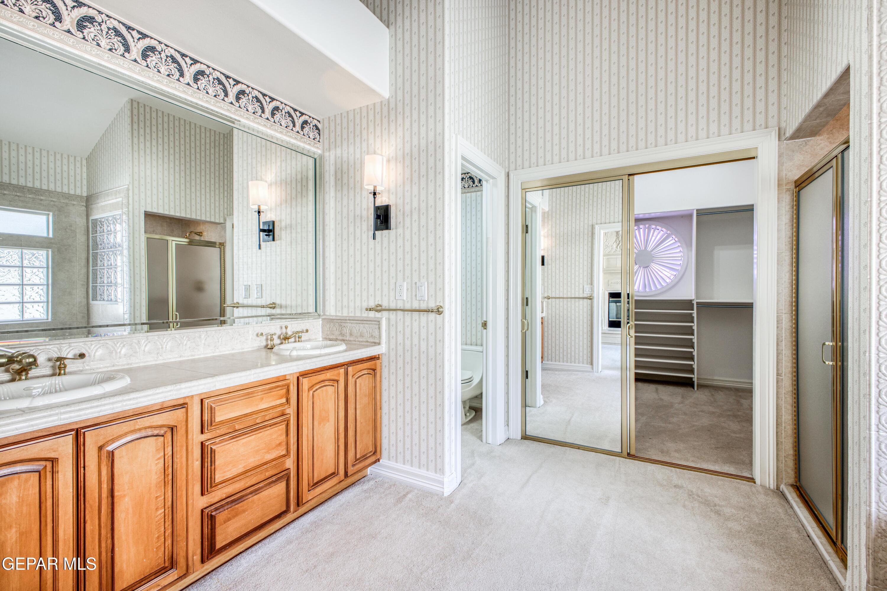 6565 Eagle Ridge Drive El Paso, TX 79912 - Photo 28 of 60 a spacious bathroom with a double vanity sink a large mirror and a shower
