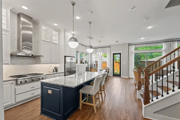 a kitchen with stainless steel appliances granite countertop a stove a sink dishwasher and a refrigerator with wooden floor