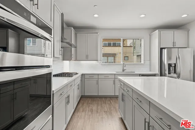 a kitchen with granite countertop a sink stove refrigerator and cabinets