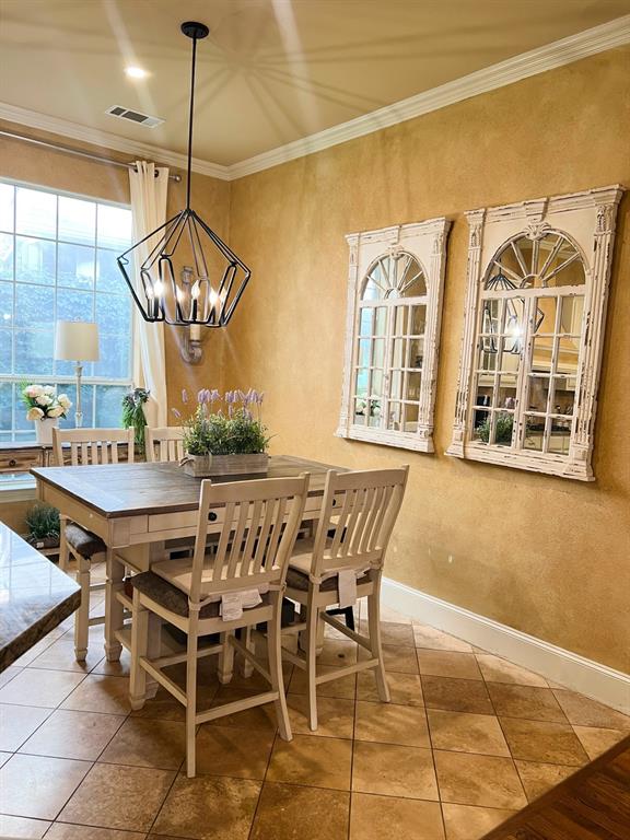 1625 Roma Lane Allen, TX 75013 - Photo 5 of 10 Dining area featuring a contemporary geometric pendant light fixture, large windows with white trim, crown molding, and light-toned floor tiling