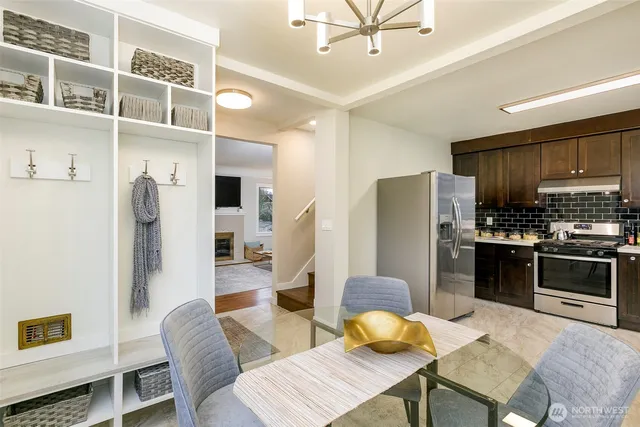 a kitchen with stainless steel appliances granite countertop a refrigerator a stove a sink dishwasher a dining table and chairs with wooden floor