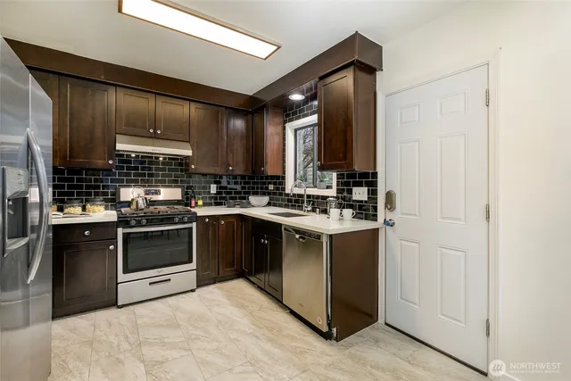 a kitchen with stainless steel appliances granite countertop a stove a sink and a refrigerator