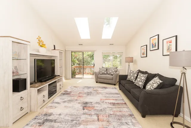a living room with furniture a flat screen tv and a floor to ceiling window