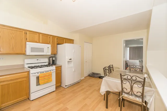 a kitchen with stainless steel appliances kitchen island granite countertop a stove a refrigerator and white cabinets with wooden floor