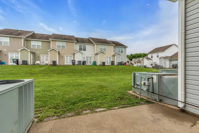 a view of a white house next to a yard with big trees