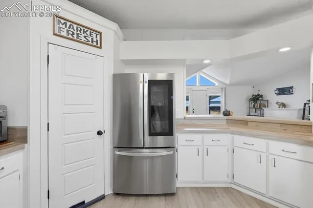 a kitchen with white cabinets and refrigerator