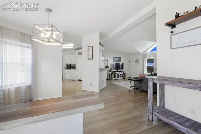 a dining room with wooden floor a chandelier a wooden table and chairs