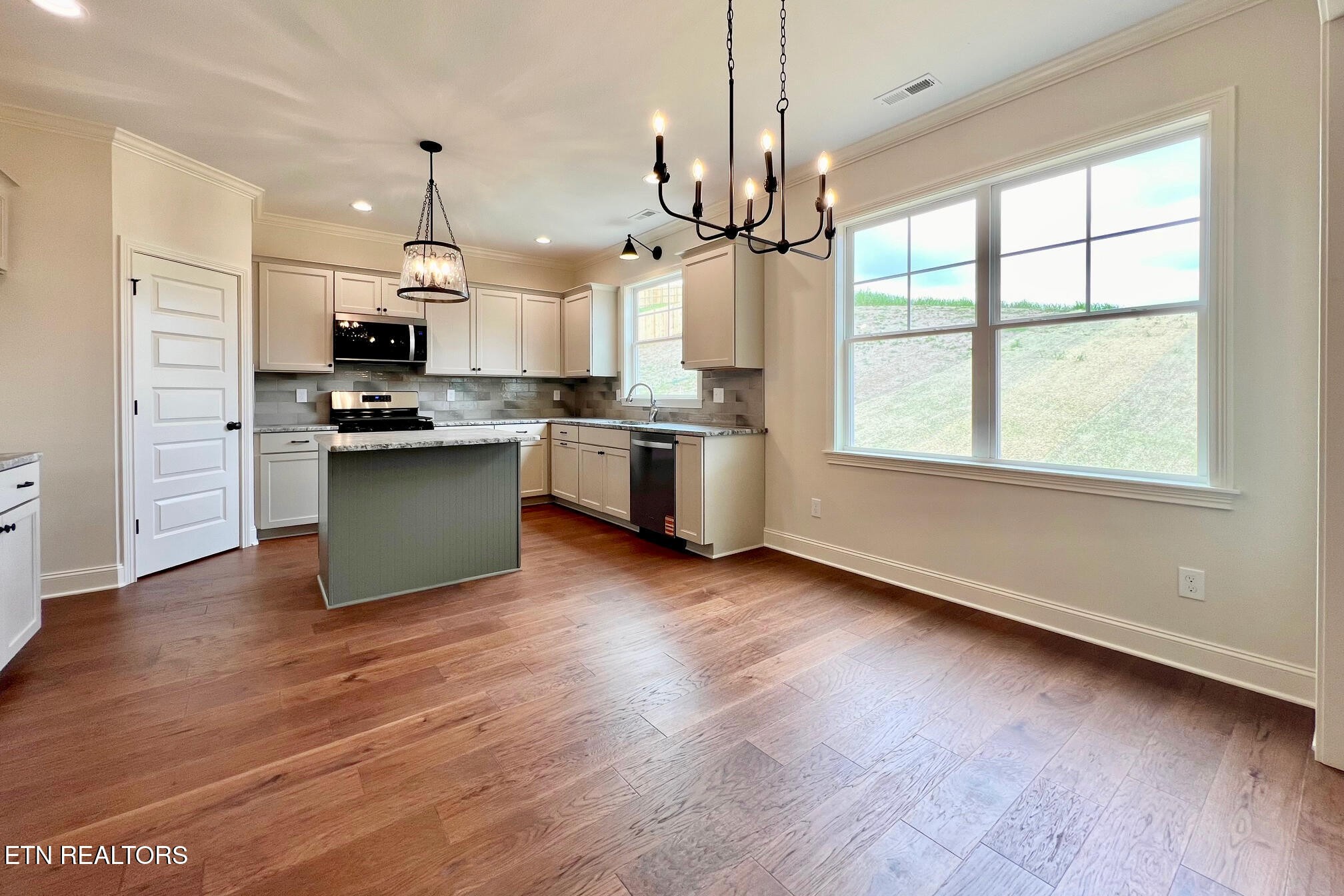 1209 Madison Oaks Road Knoxville, TN 37924 - Photo 14 of 35 a open kitchen with stainless steel appliances granite countertop a stove a sink dishwasher a refrigerator and a wooden floor