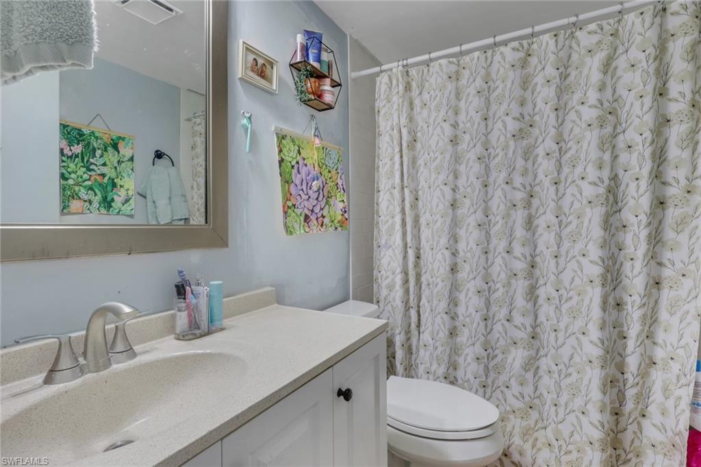 1211 Commonwealth Circle, Unit C201 Naples, FL 34116 - Photo 11 of 23 a bathroom with a sink a toilet and a shower curtain