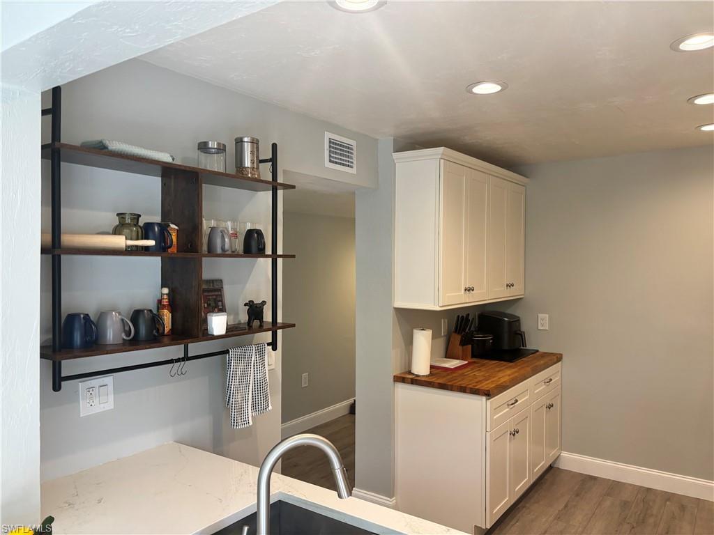 1211 Commonwealth Circle, Unit C201 Naples, FL 34116 - Photo 4 of 23 a kitchen with stainless steel appliances a white cabinets and a wooden floor