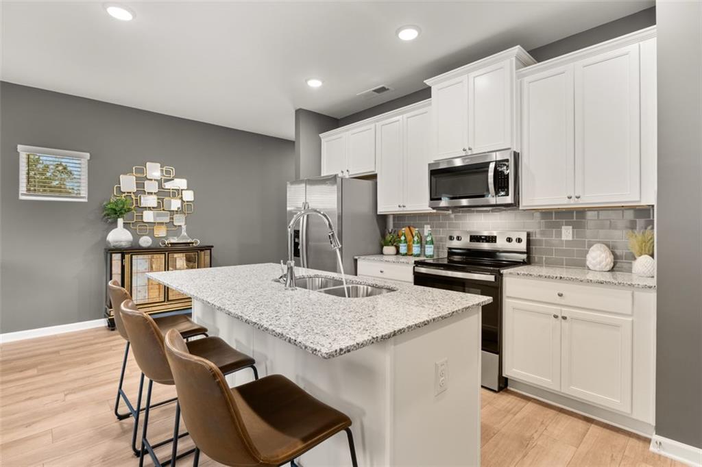 269 Epping Street, Unit 81 Stockbridge, GA 30281 - Photo 15 of 64 a kitchen with a stove a sink a microwave a refrigerator and white cabinets with wooden floor