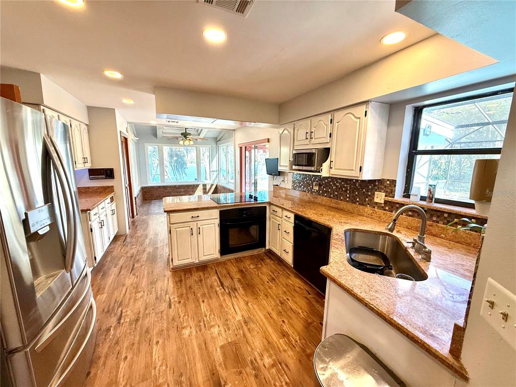 2395 Windward Cove Kissimmee, FL 34746 - Photo 16 of 62 a kitchen with stainless steel appliances granite countertop a stove top oven a sink a refrigerator white cabinets and wooden floor