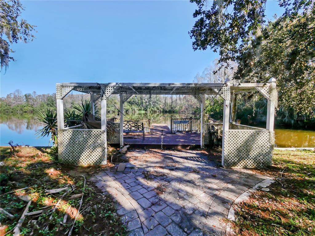 2395 Windward Cove Kissimmee, FL 34746 - Photo 51 of 62 a view of a patio with table and chairs under an umbrella with large trees