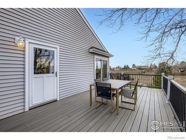 a view of a roof deck with table and chairs a barbeque with wooden floor and fence
