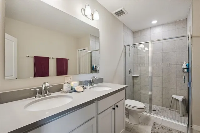 a bathroom with a granite countertop sink a toilet a mirror and shower