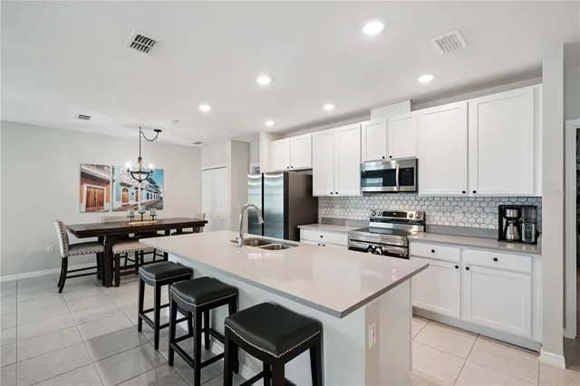 a kitchen with stainless steel appliances kitchen island granite countertop a stove top oven a sink a refrigerator with a dining table and chairs
