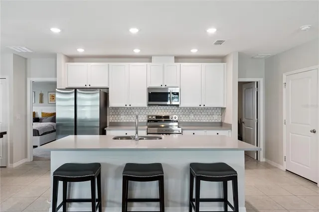 a kitchen with stainless steel appliances granite countertop a sink a stove a refrigerator cabinets and chairs
