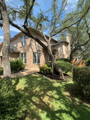 a view of a white house next to a yard with a tree