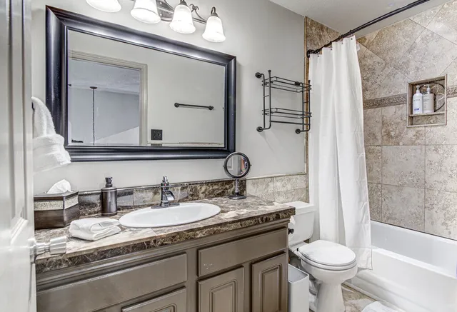 a bathroom with a granite countertop sink toilet and shower