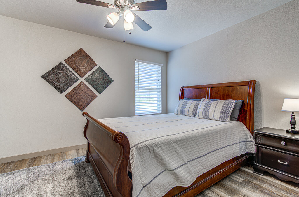 7712 Earp Way Austin, TX 78729 - Photo 31 of 40 a bedroom with a bed and a lamp on dresser