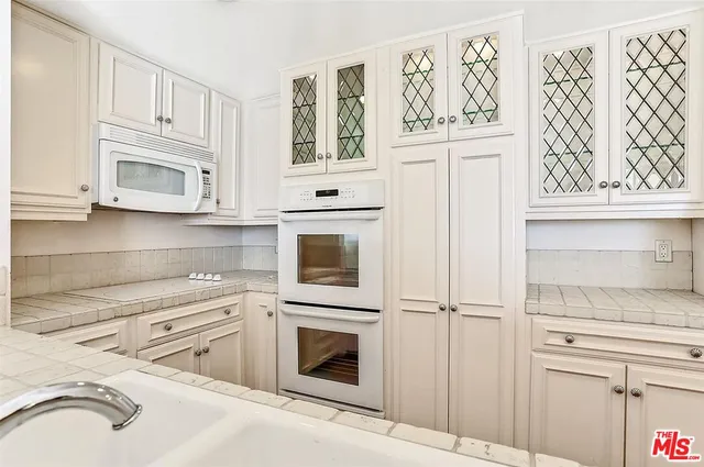 a kitchen with stainless steel appliances white cabinets and window