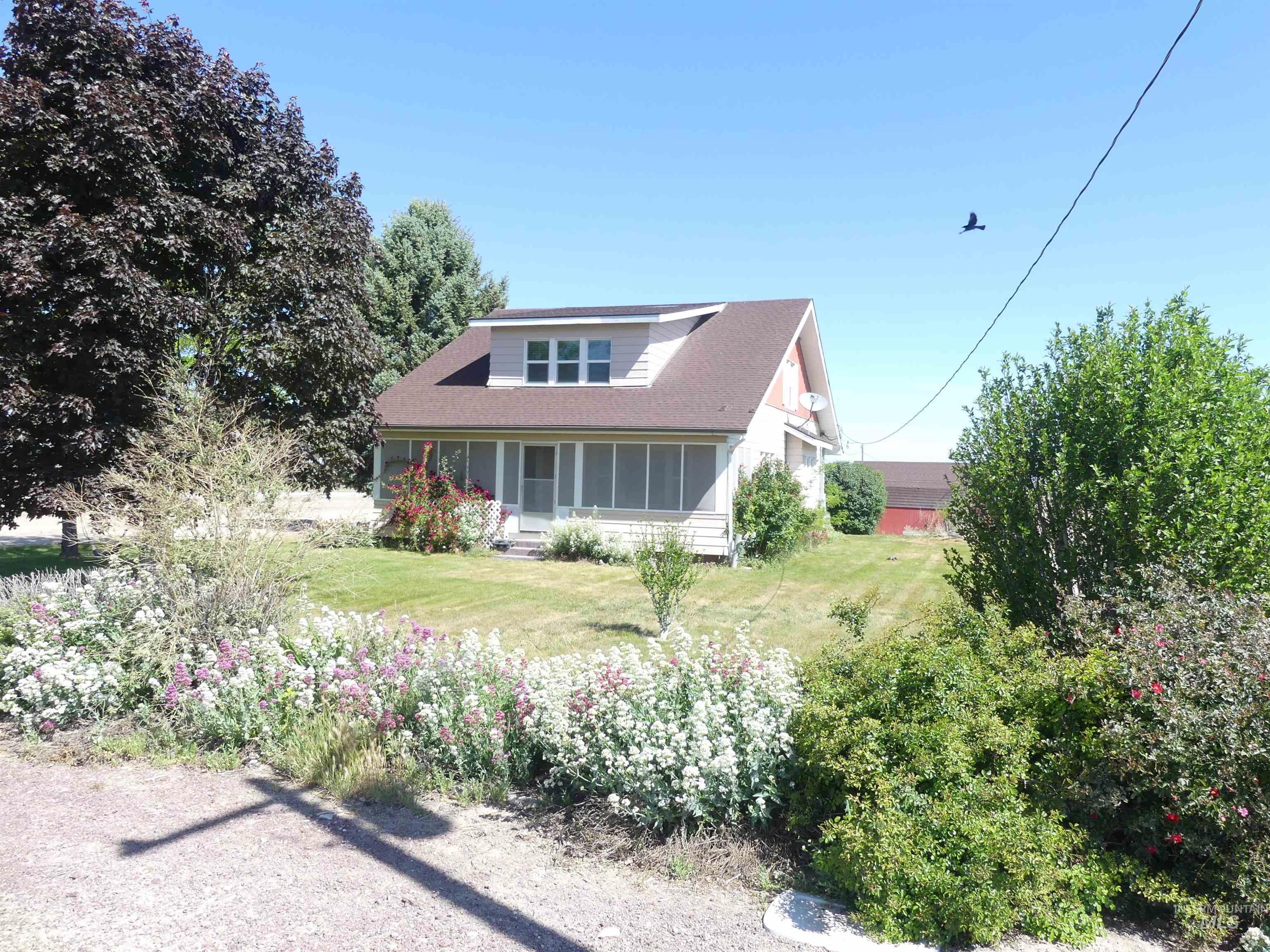 16478 Locust Lane Caldwell, ID 83607 - Photo 1 of 1 Cottage-style residence featuring a dormer window, screened-in porch, and a gravel driveway