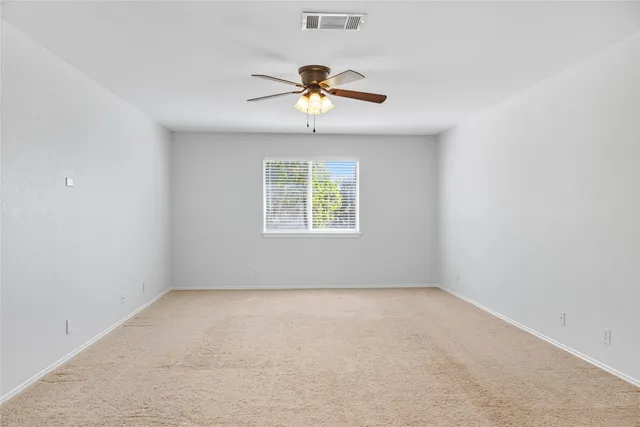 an empty room with a window and a ceiling fan