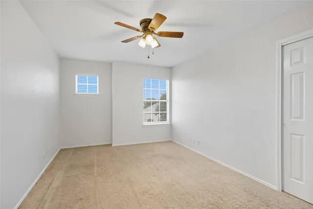 an empty room with a ceiling fan and a window