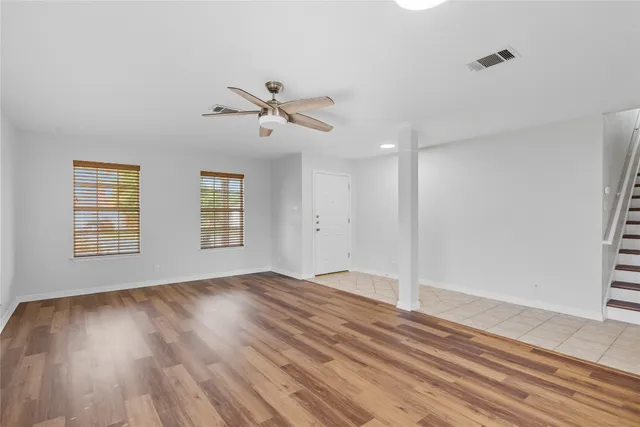 a view of empty room with wooden floor and fan