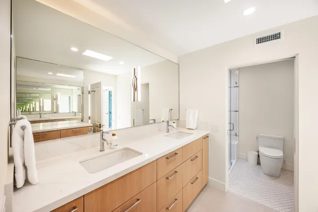 a bathroom with a double vanity sink toilet and a mirror