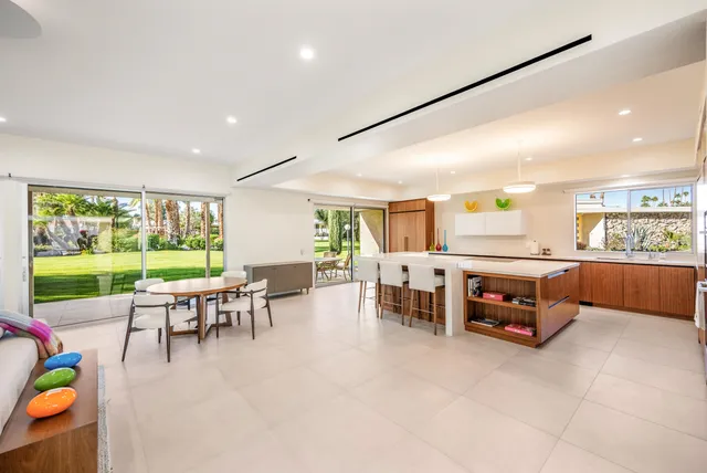 a dining hall with furniture a window and a kitchen view