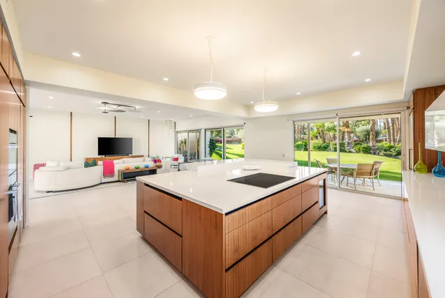 a large white kitchen with a large island oven a sink and a large window