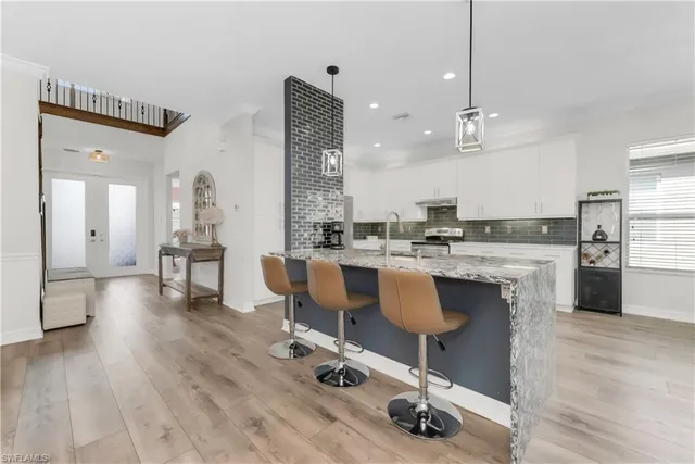 a dining hall with stainless steel appliances kitchen island granite countertop a dining table chairs and view living room