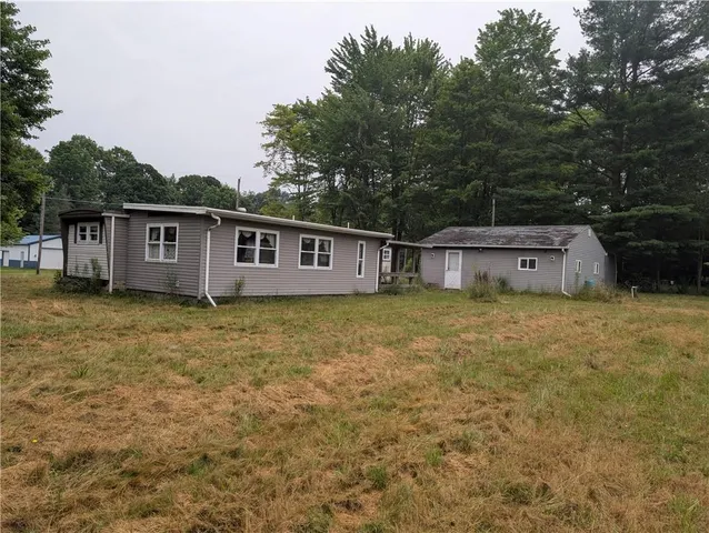 a front view of house with yard and trees in the background