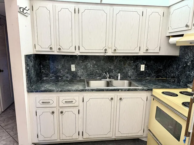 a kitchen with granite countertop white cabinets and sink