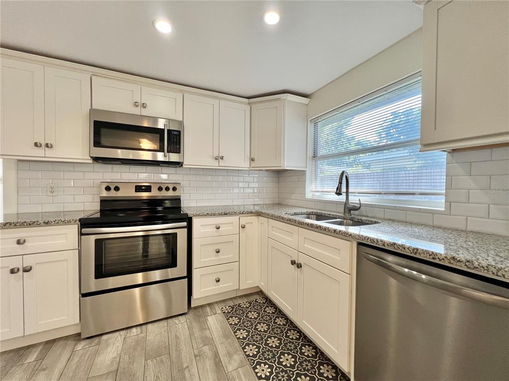 1716 West Nassau Street Tampa, FL 33607 - Photo 7 of 25 a kitchen with granite countertop a sink a stove and cabinets