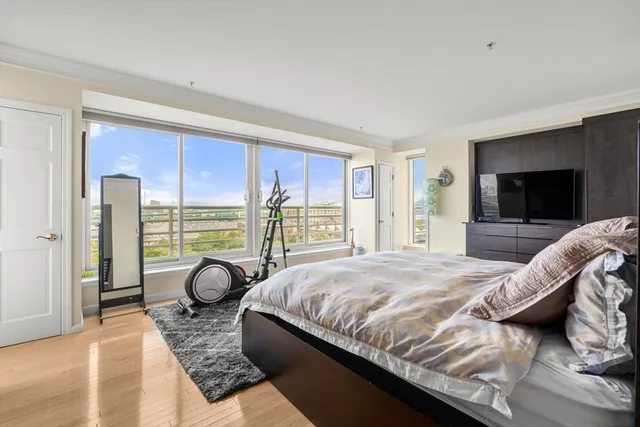 a bedroom with a bed and large windows