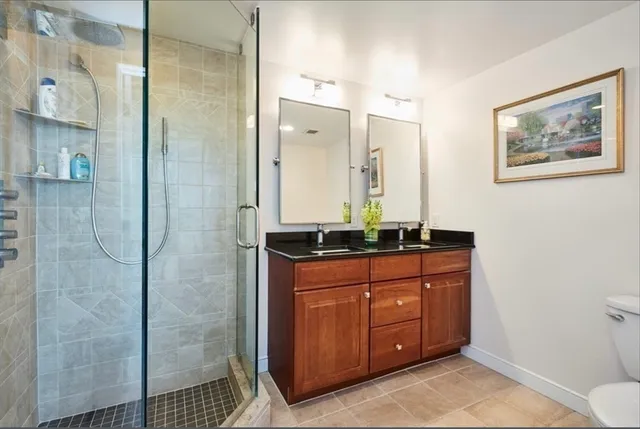 a bathroom with a granite countertop sink a mirror a vanity and a shower