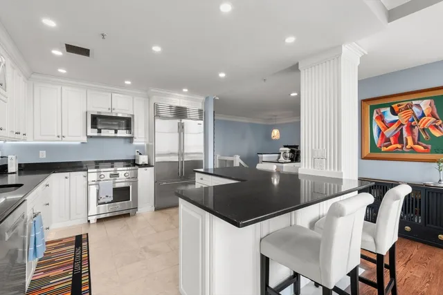 a kitchen with stainless steel appliances granite countertop a stove top oven a sink a dining table and chairs