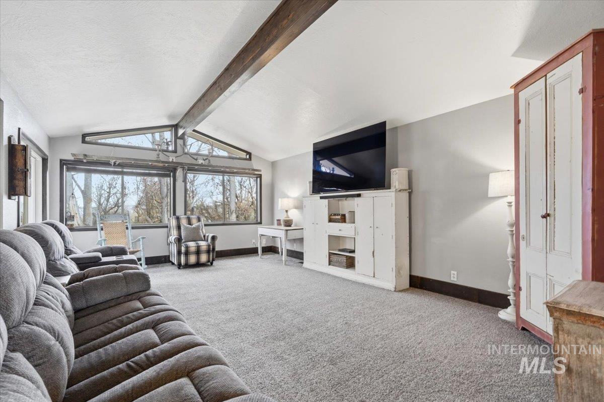 7771 Elmore Road Fruitland, ID 83619 - Photo 8 of 48 Carpeted living area featuring baseboards and beam ceiling