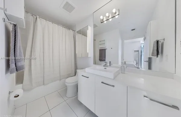 a spacious bathroom with a double vanity sink toilet and a mirror