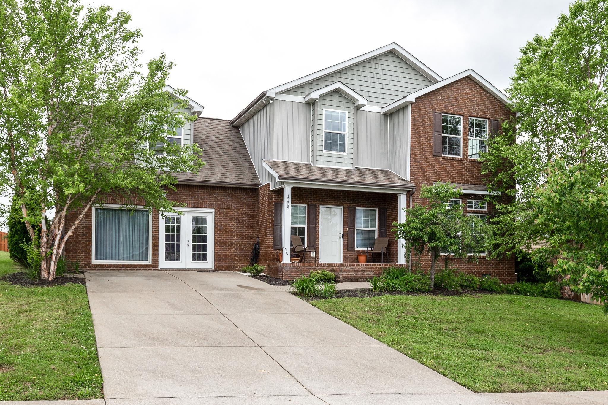 a front view of a house with a yard and trees